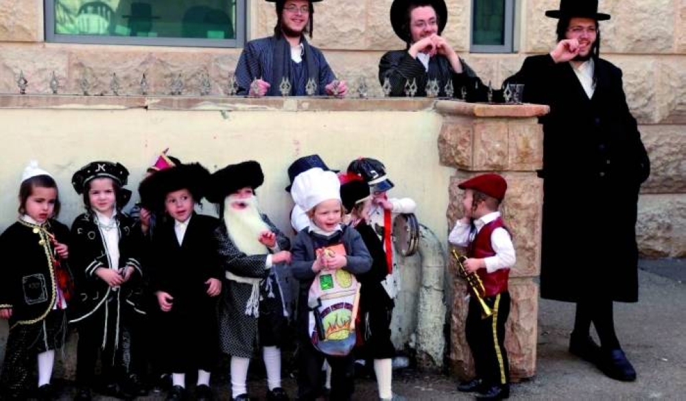 Ultra-Orthodox Jewish children dressed in costumes celebrating Purim walk in a yard at their school, one day ahead of the official holiday, in the Mea Shearim neighbourhood in Jerusalem on February 24, 2021. - The carnival-like Purim holiday is celebrated with parades and costume parties to commemorate biblical story of the deliverance of the Jewish people from a plot to exterminate them in the ancient Persian empire, as recorded in the Book of Esther. (Photo by MENAHEM KAHANA / AFP) (Photo by MENAHEM KAHANA/AFP via Getty Images)
