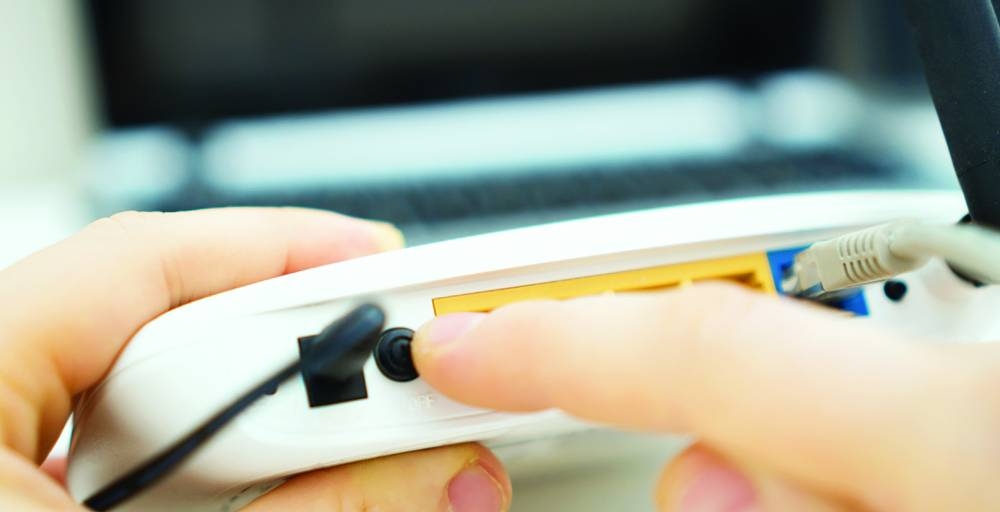 Man pressing power button on the wifi router.